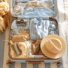 maleta abierta con ropa, sombrero, camara de fotos, accesorios