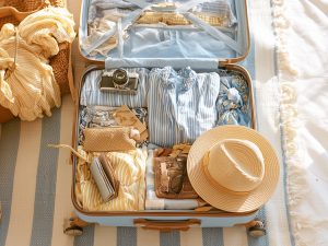 maleta abierta con ropa, sombrero, camara de fotos, accesorios